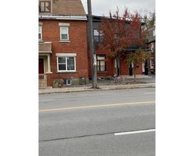 A street view with a red brick building and a bicycle parked on the sidewalk.