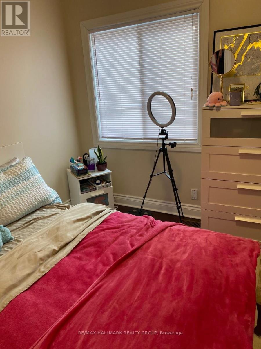 A bedroom with a red bedspread and a tripod in the corner.