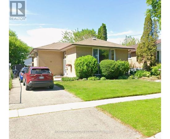 A red car is parked in front of a house with a sign that says REALTOR.
