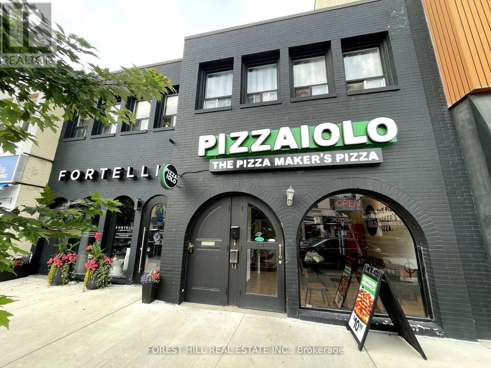A pizza shop named Pizzaiolo is located in a building with a black facade.