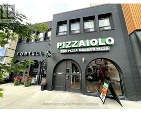 A pizza shop named Pizzaiolo is located in a building with a black facade.