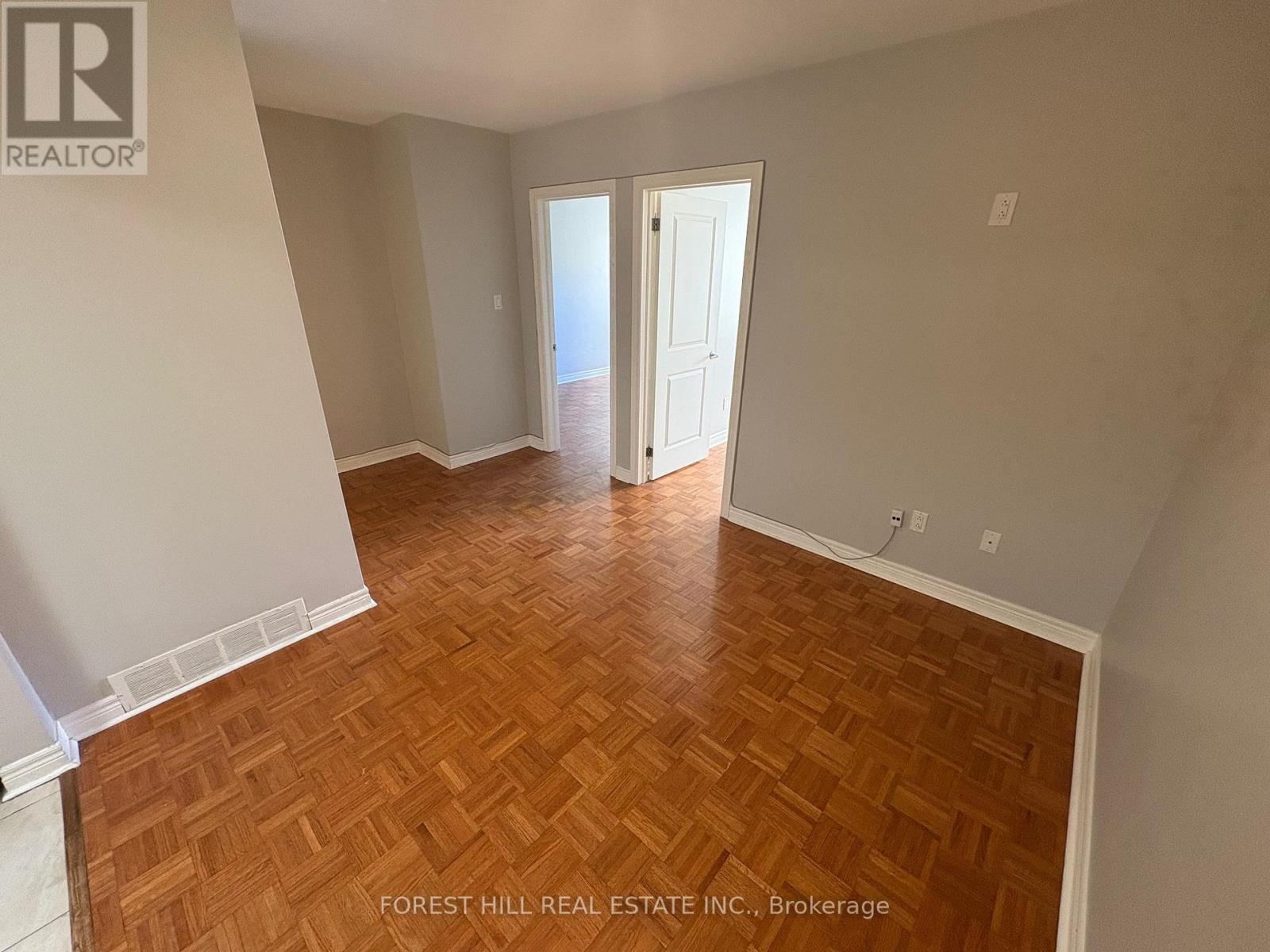 A room with wooden flooring and a doorway leading to another room.