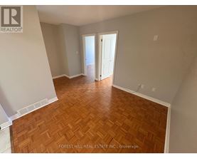 A room with wooden flooring and a doorway leading to another room.