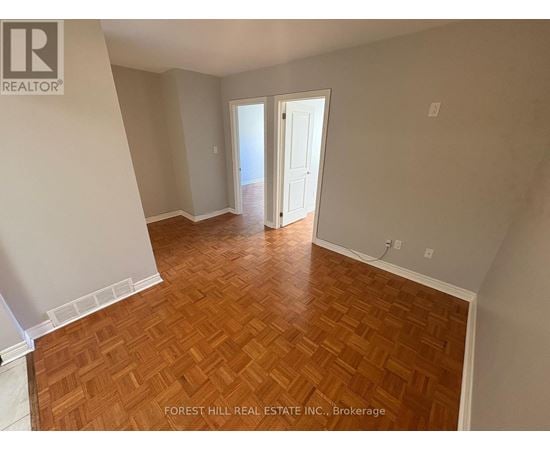 A room with wooden flooring and a doorway leading to another room.