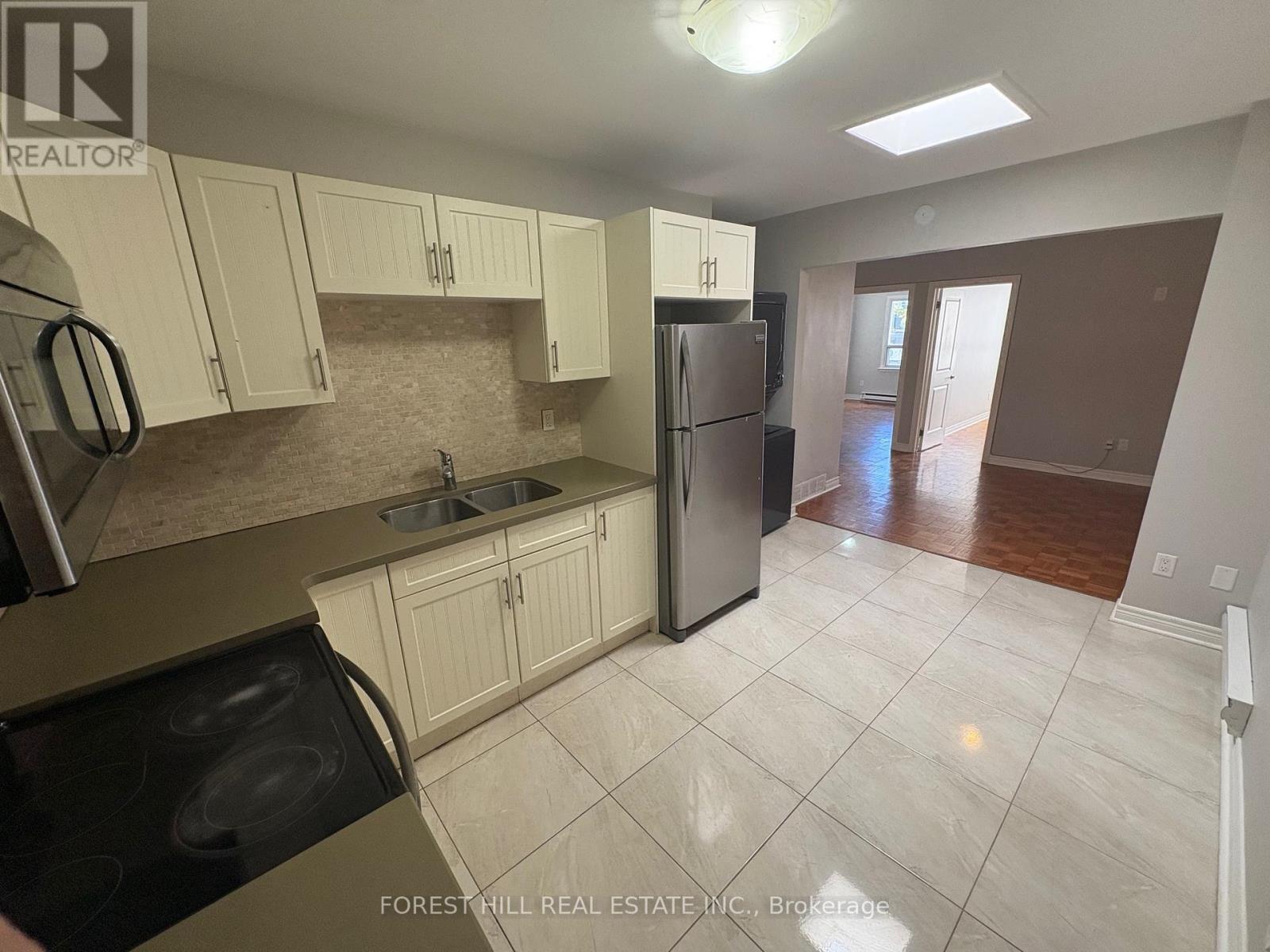 A kitchen with white cabinets and a refrigerator.