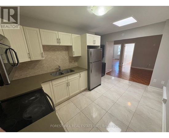 A kitchen with white cabinets and a refrigerator.