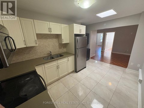 A kitchen with white cabinets and a refrigerator.