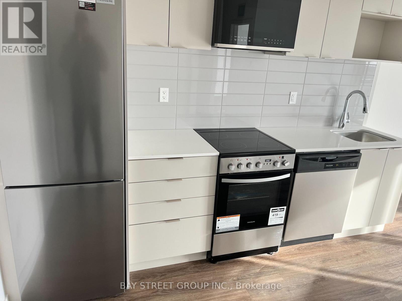 A kitchen with a stainless steel refrigerator and a black countertop.