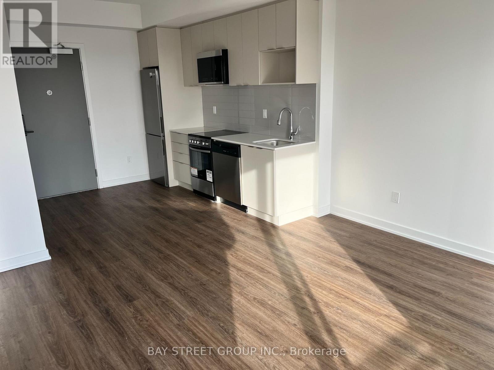A kitchen with a refrigerator, microwave, oven, and sink.