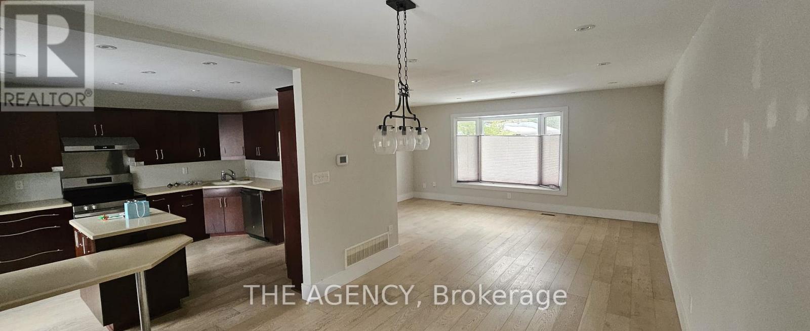 A spacious kitchen with dark brown cabinets and a dining table.