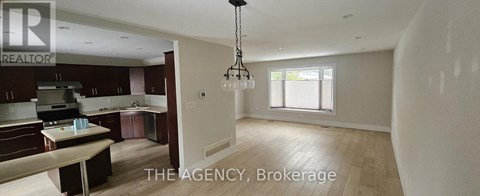 A spacious kitchen with dark brown cabinets and a dining table.