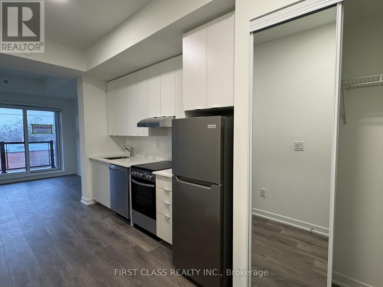 A kitchen with a refrigerator, sink, and stove.