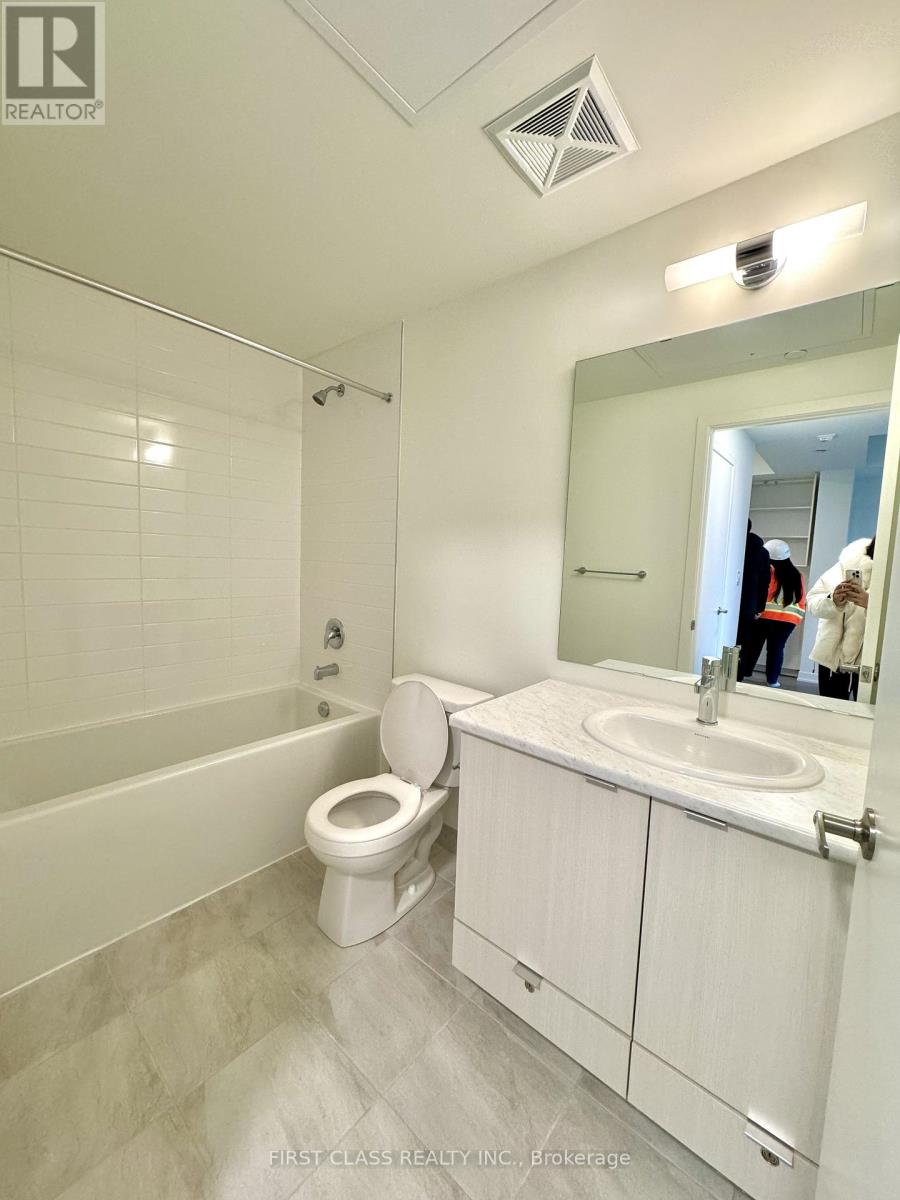 A white bathroom with a toilet, sink, and mirror.
