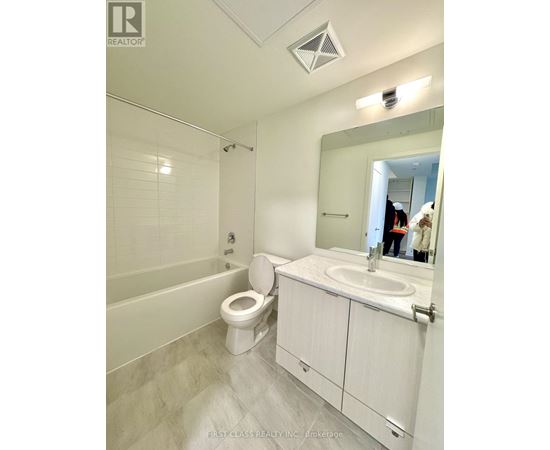 A white bathroom with a toilet, sink, and mirror.