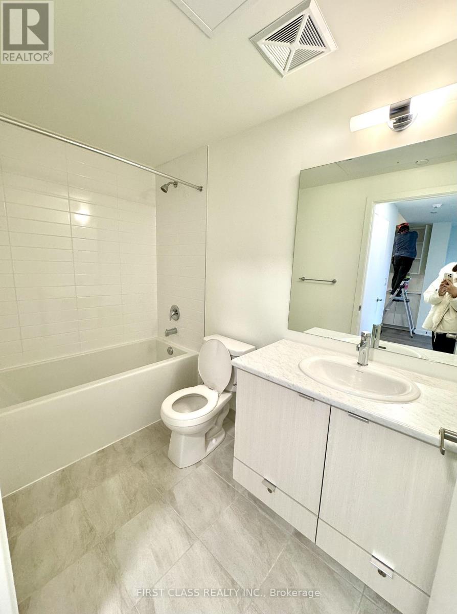 A bathroom with a toilet, sink, and mirror.