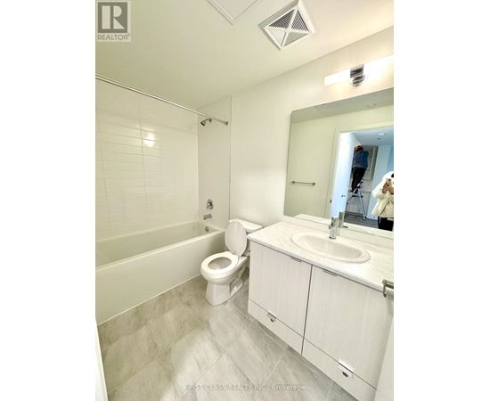 A bathroom with a toilet, sink, and mirror.
