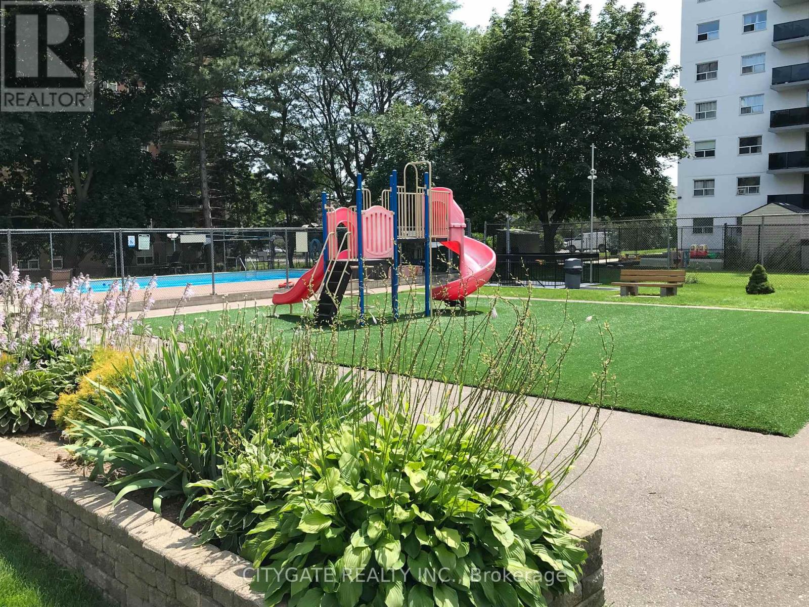 A playground with a red slide and a green lawn.
