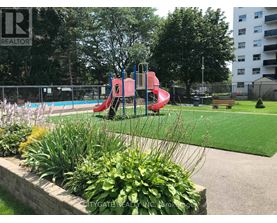 A playground with a red slide and a green lawn.