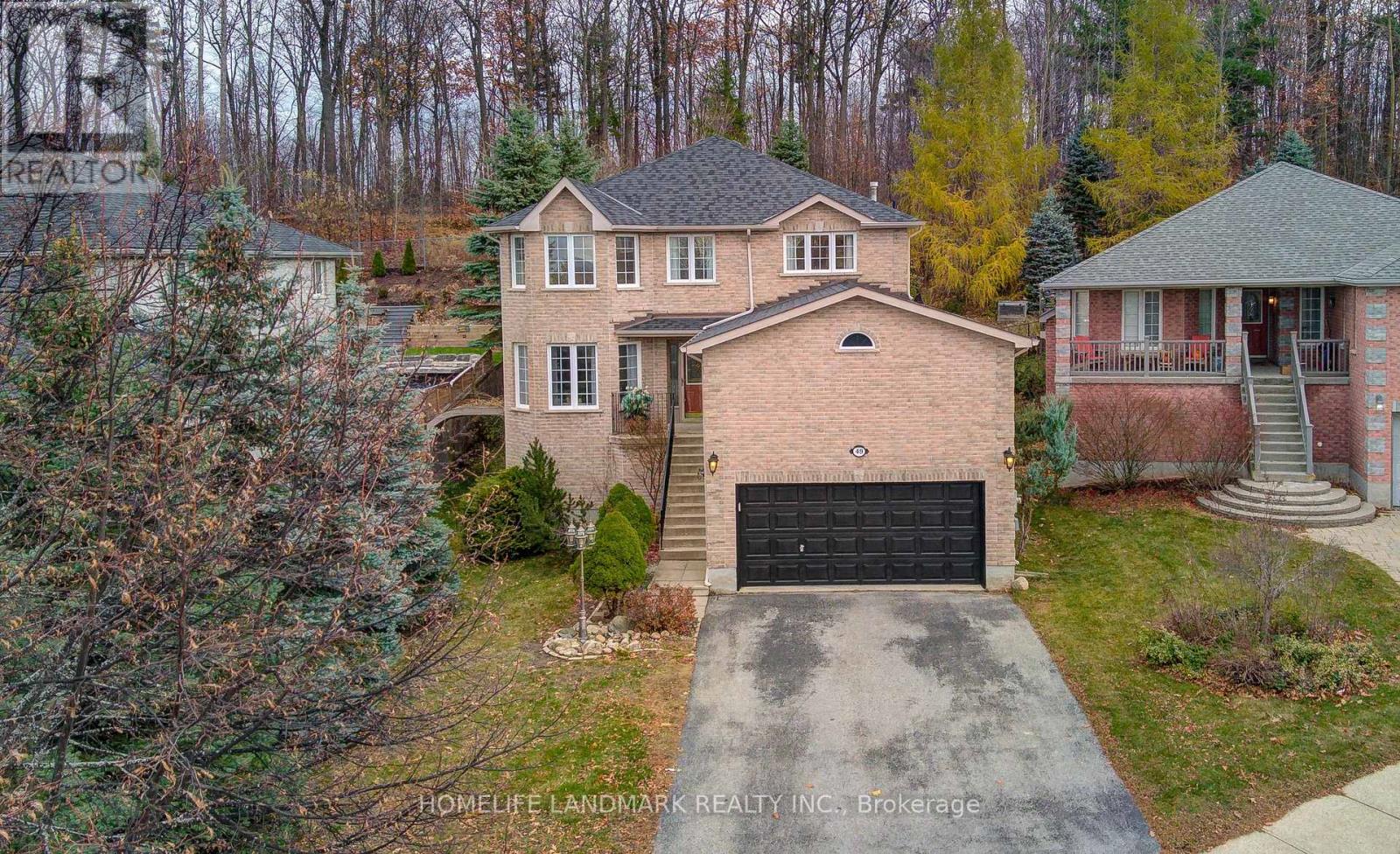 A house with a garage is surrounded by trees.