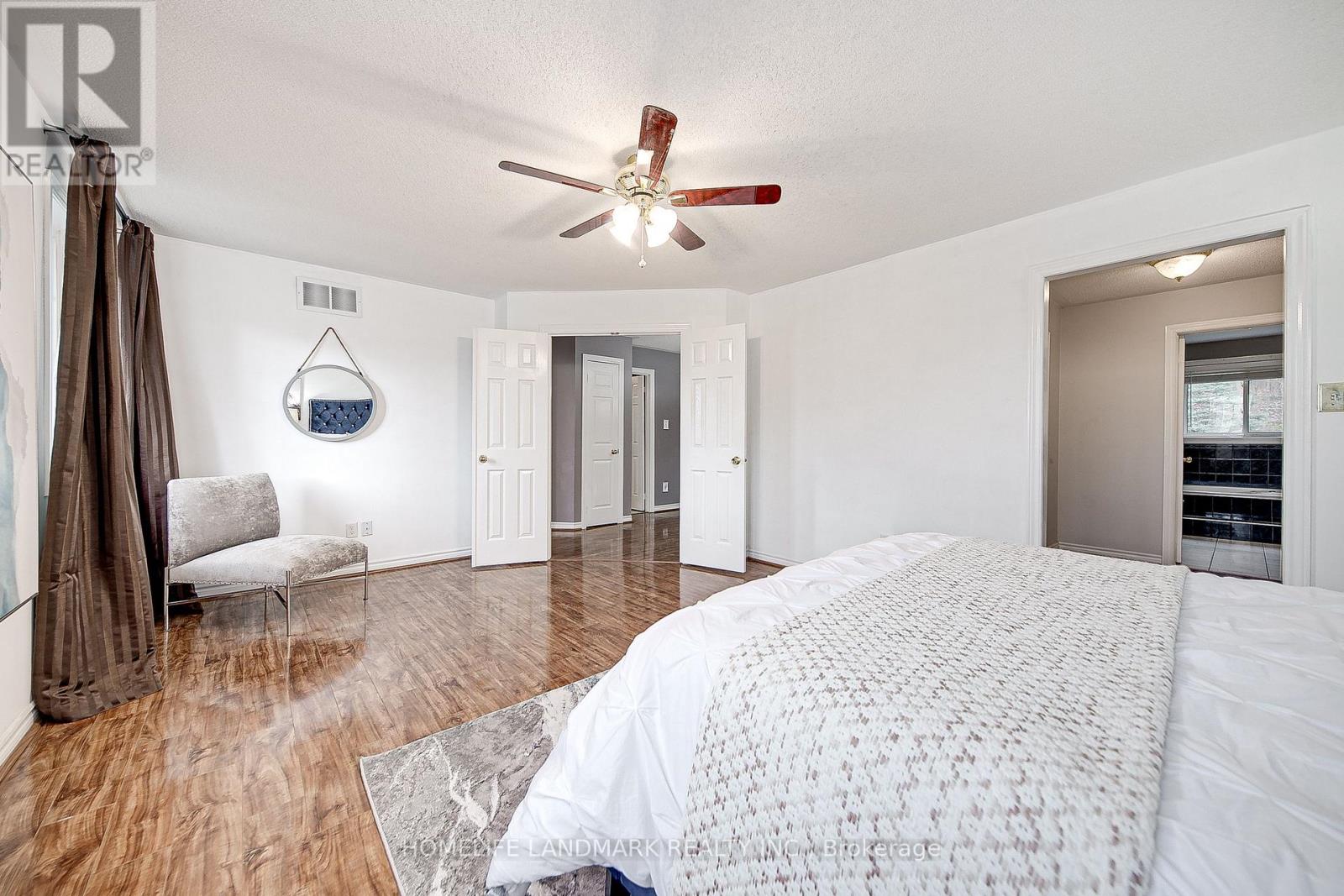 A bedroom with a large bed and a ceiling fan.