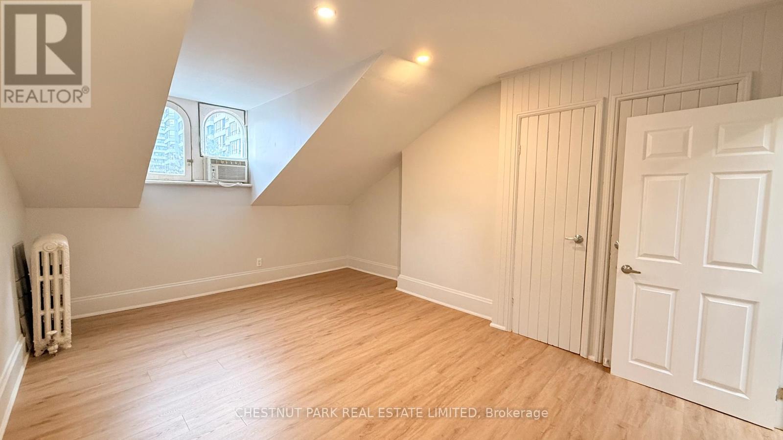 A room with a white door and a window with a view of a building outside.