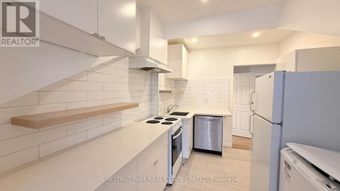A white kitchen with a stove top oven and a refrigerator.