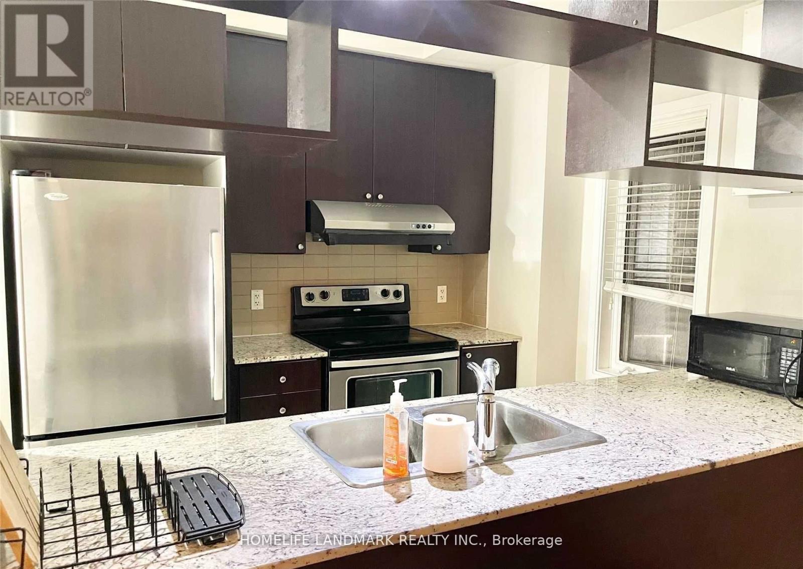 A kitchen with a stainless steel refrigerator and a granite counter top.
