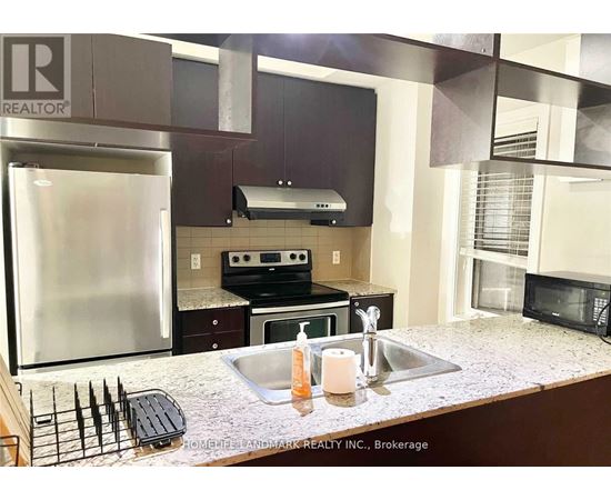 A kitchen with a stainless steel refrigerator and a granite counter top.