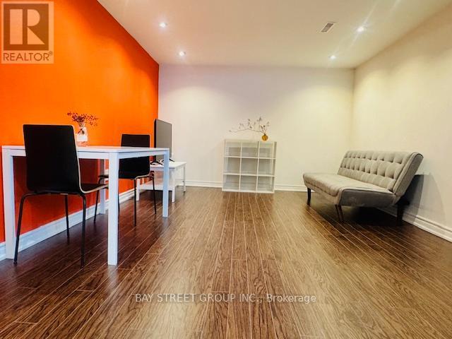 A room with a white table and chairs with an orange wall.