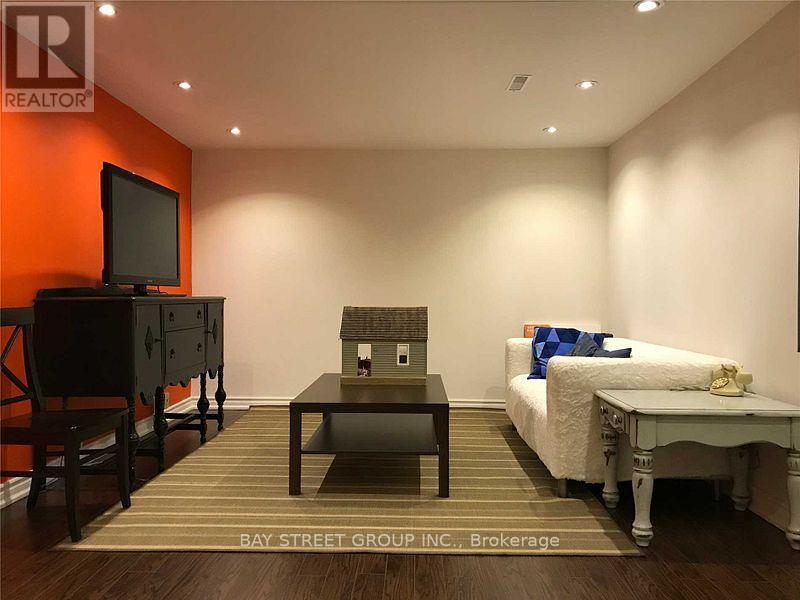 A bedroom with a bed, a dresser, a nightstand, a chair, a coffee table, and a television.