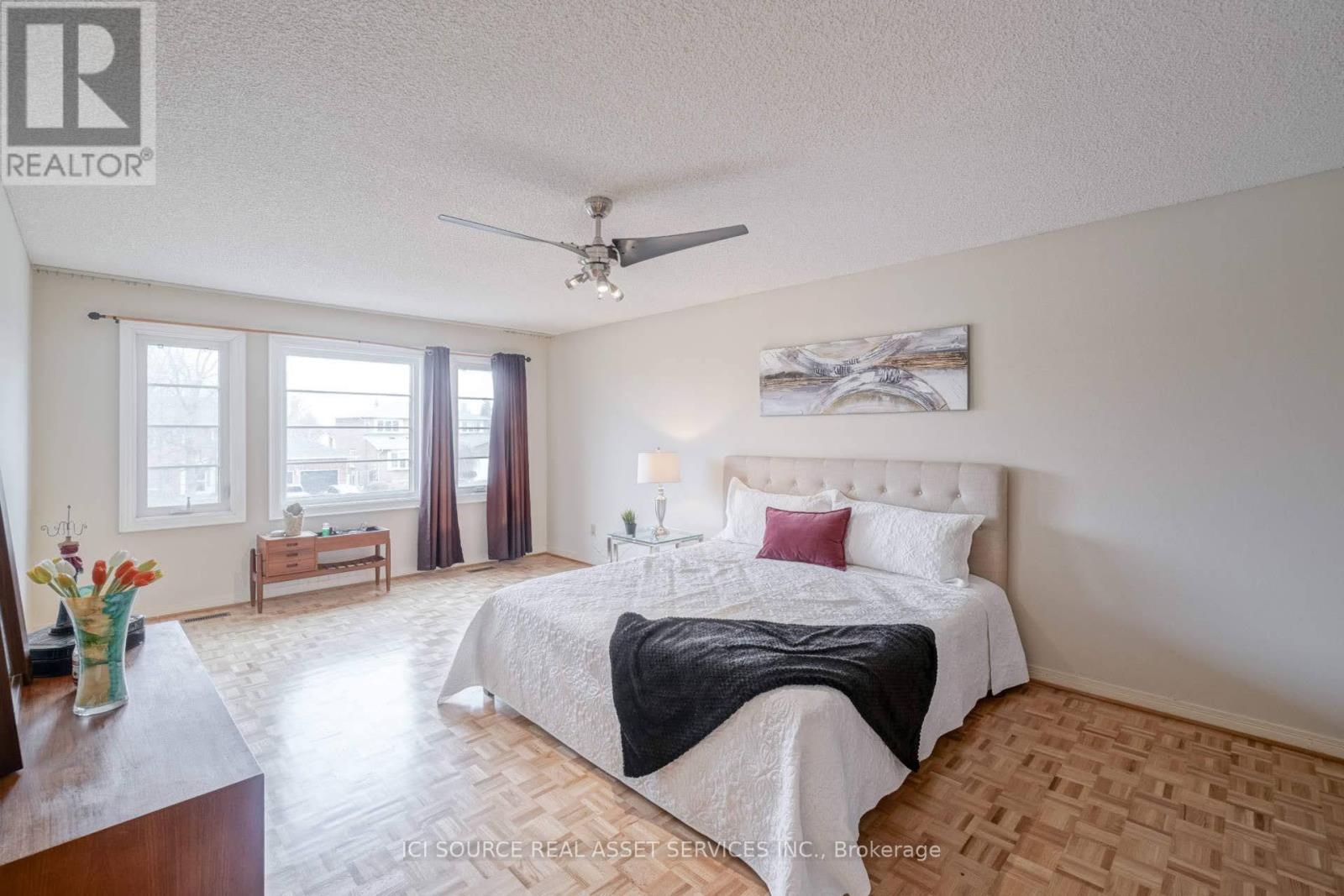 A bedroom with a large bed and a ceiling fan.