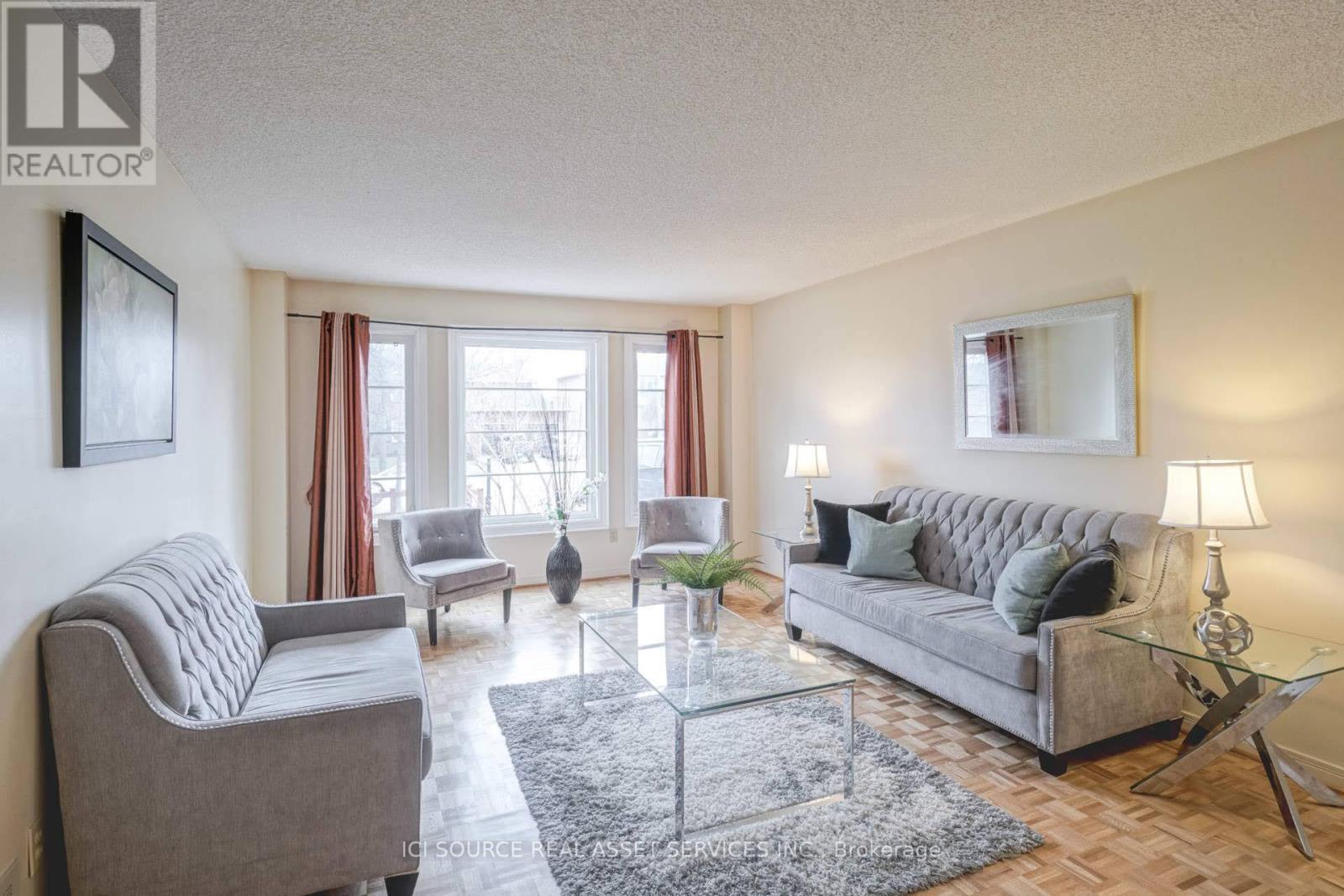 A living room with a grey couch, a glass coffee table, and a grey armchair.