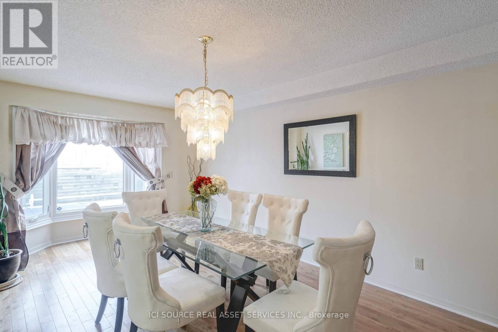 A dining room with a glass table and white chairs.