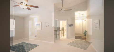 A spacious room with a ceiling fan and a rug on the floor.