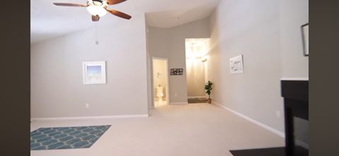 A living room with a ceiling fan and a rug on the floor.