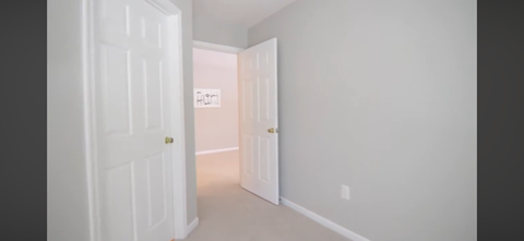 A hallway with a white door on the left and a white door on the right.