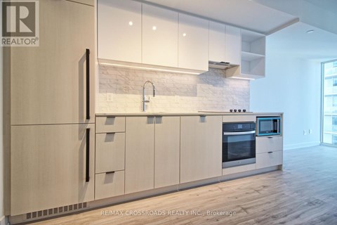A modern kitchen with white cabinets and a wooden floor.