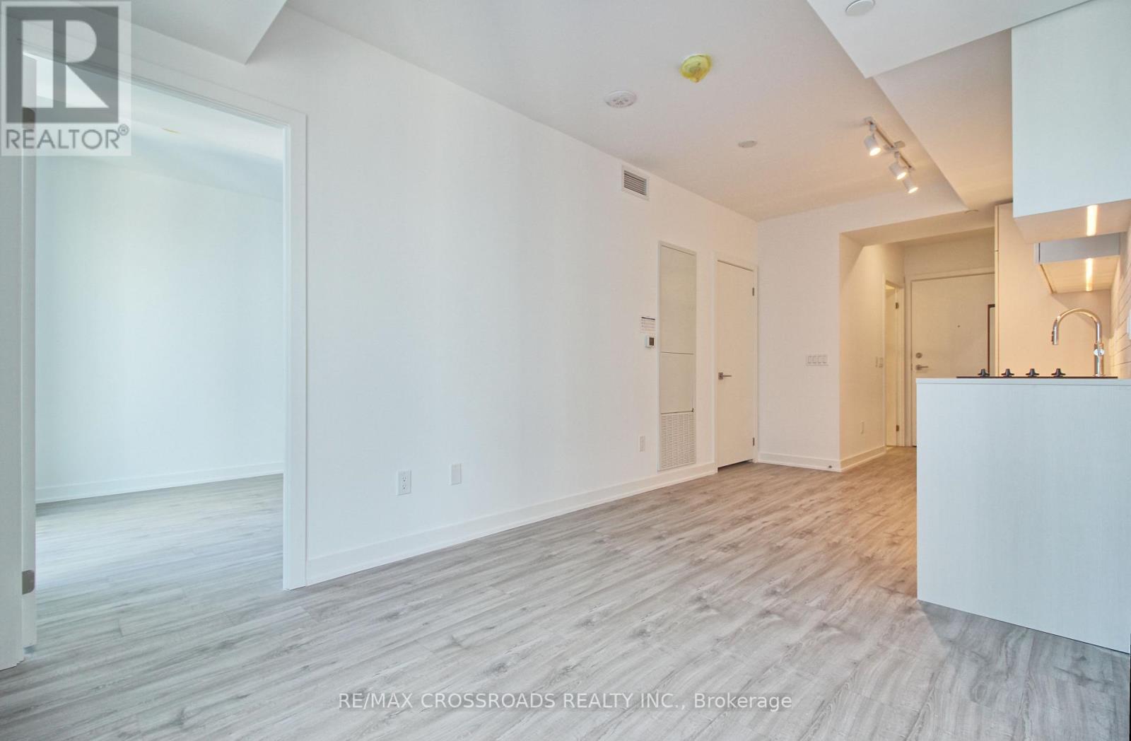A spacious room with wooden flooring and white walls.