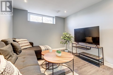 A living room with a grey couch, a wooden coffee table, and a television on a stand.