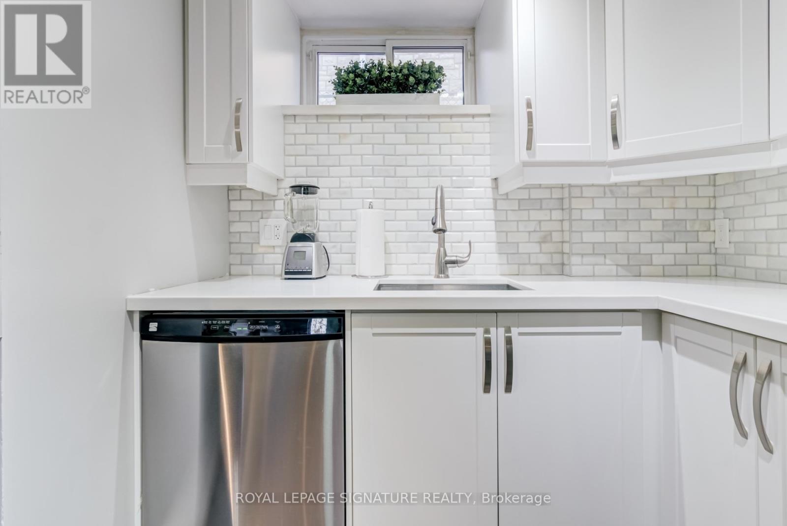 A white kitchen with a stainless steel dishwasher and a sink.
