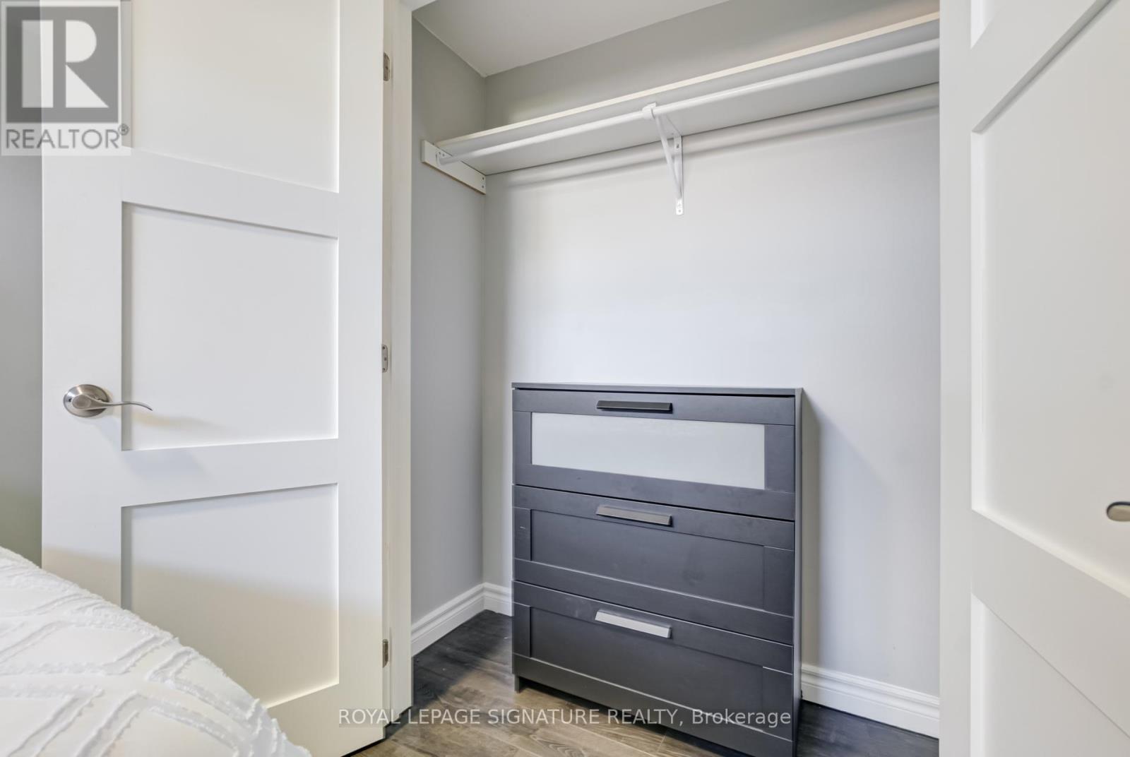 A bedroom with a white bed and a grey chest of drawers.