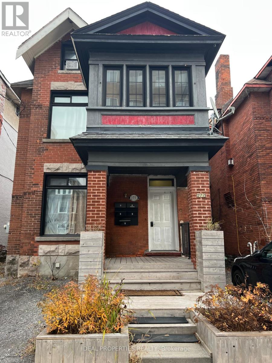 A house with a red brick exterior and a black car parked in front.