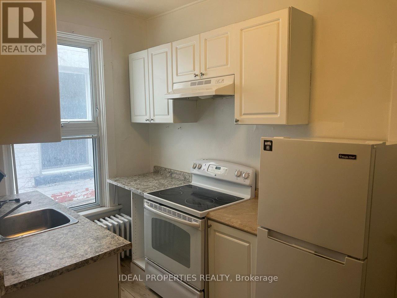 A kitchen with white cabinets and a stove top oven.