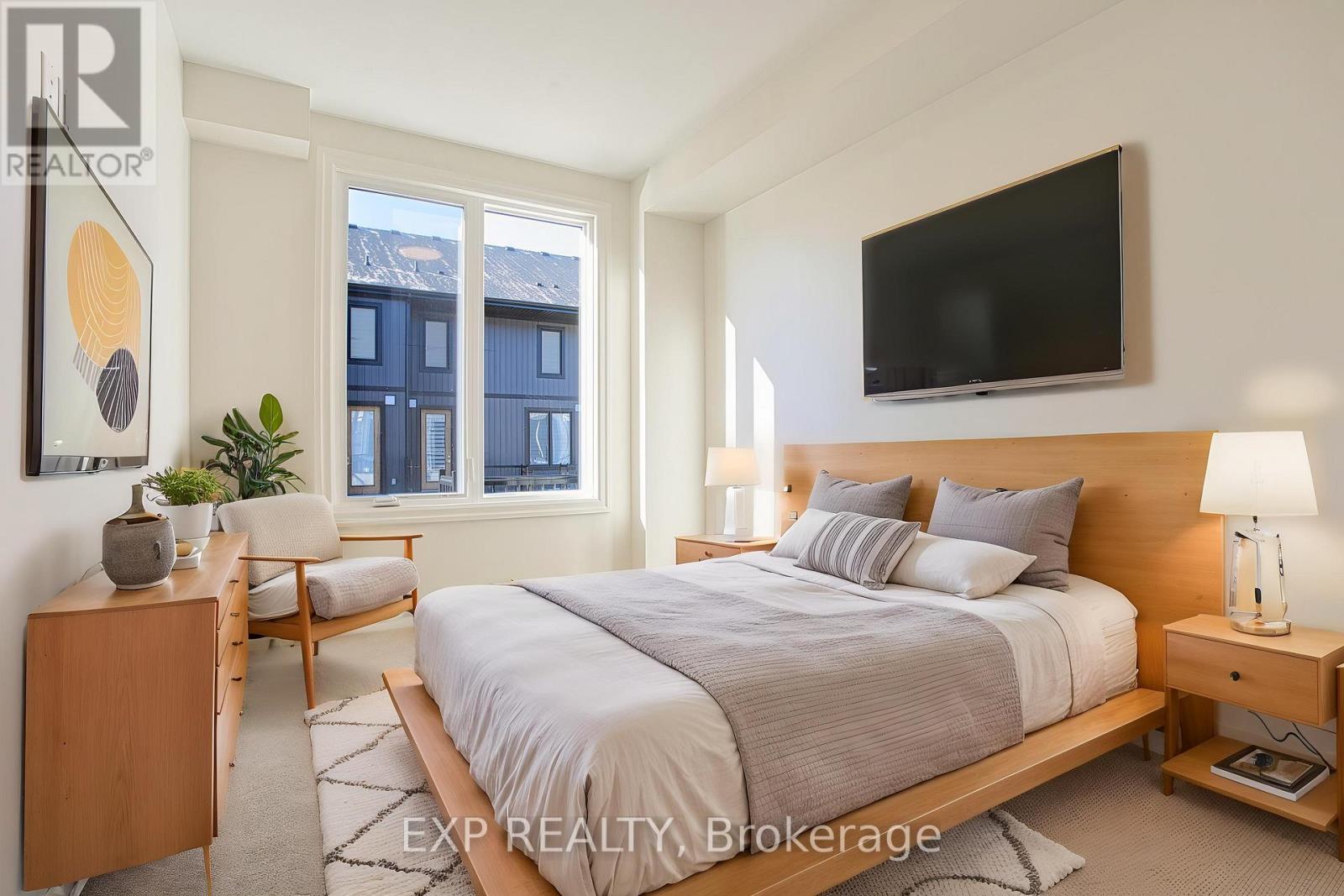 A bedroom with a large bed, a chair, and a TV mounted on the wall.