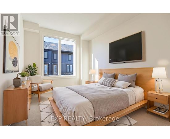 A bedroom with a large bed, a chair, and a TV mounted on the wall.