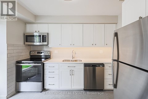 A kitchen with a refrigerator, oven, microwave, and sink.