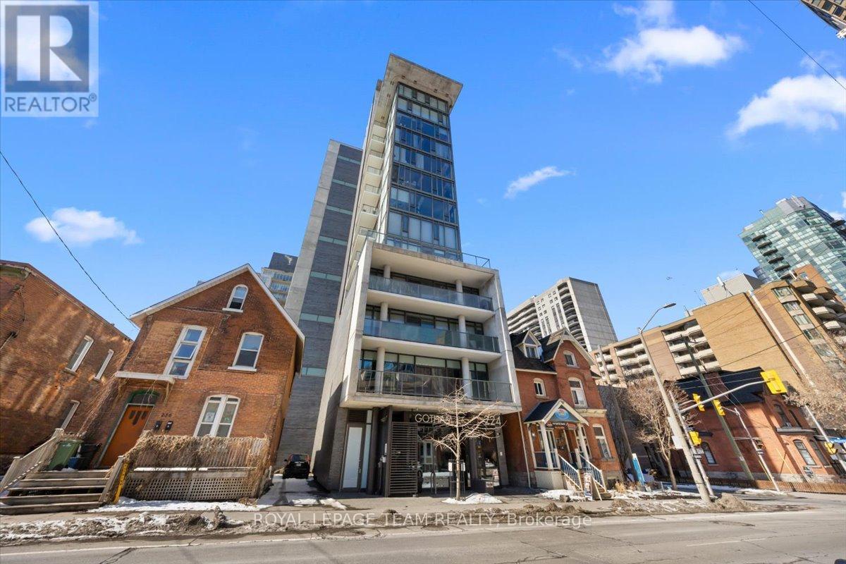 A tall building with a glass facade stands in front of a row of older brick buildings.