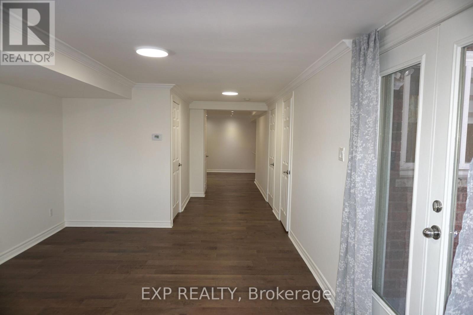 A long hallway with white walls and wood floors.