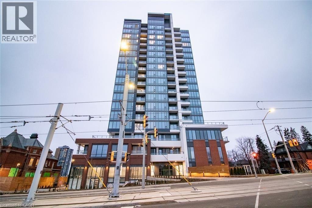 A tall building with a glass facade stands next to a smaller building with a brick facade.