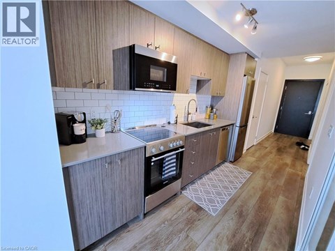 A modern kitchen with wooden cabinets and a black microwave above the stove.
